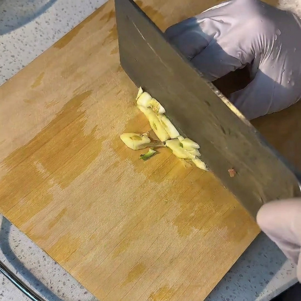 Dientes de ajo fresco siendo picados sobre una tabla de cortar de madera.