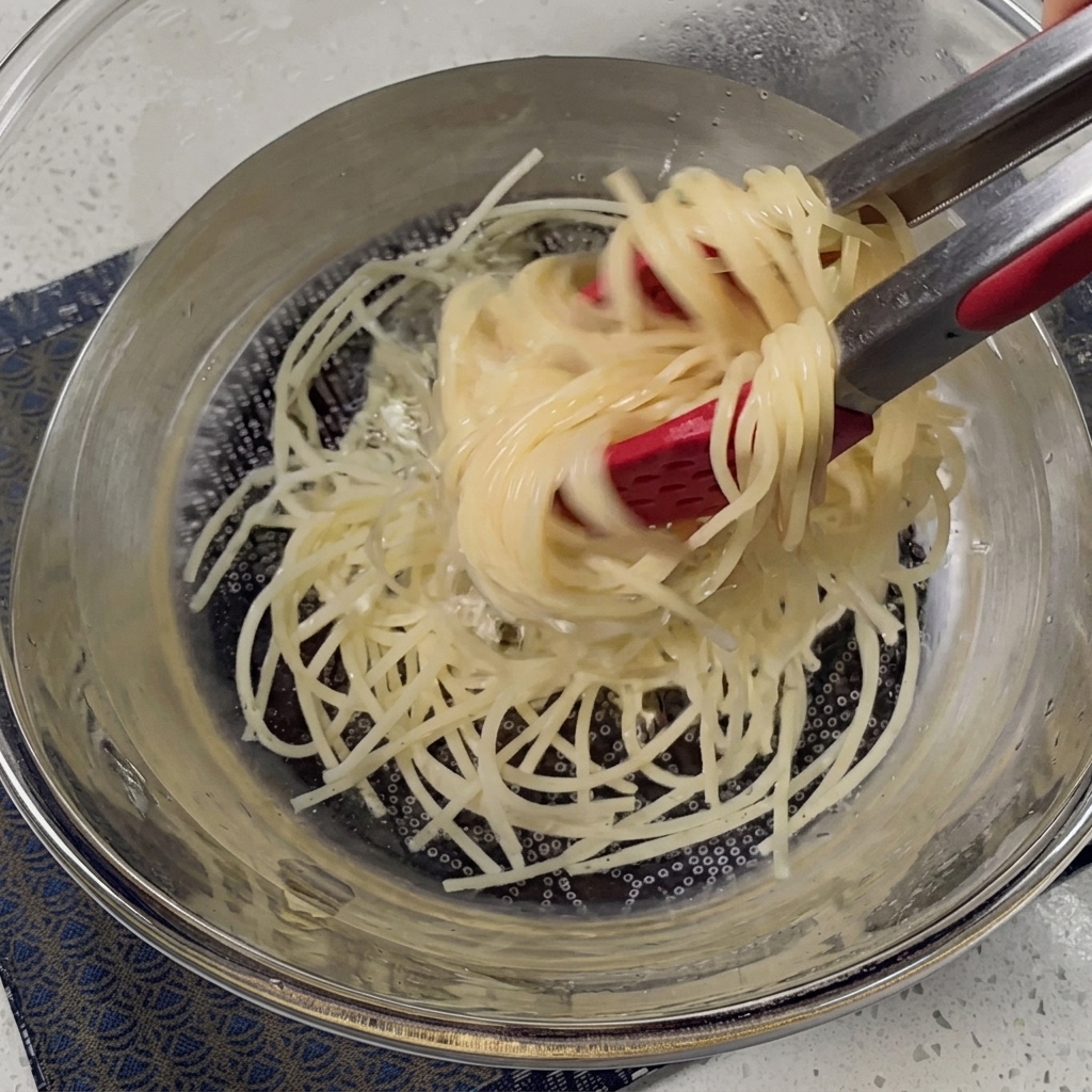 Espaguetis cocidos siendo escurridos en un colador metálico.