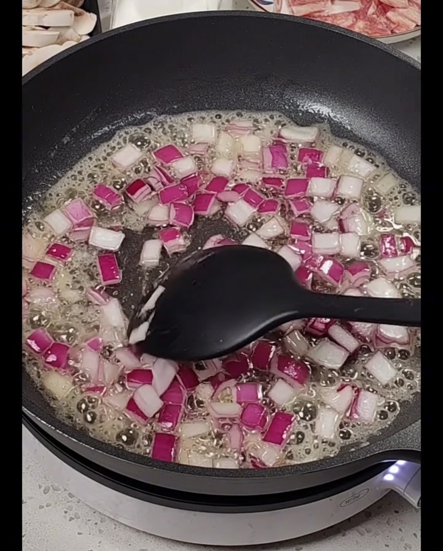Cebolla roja picada cocinándose en mantequilla derretida.