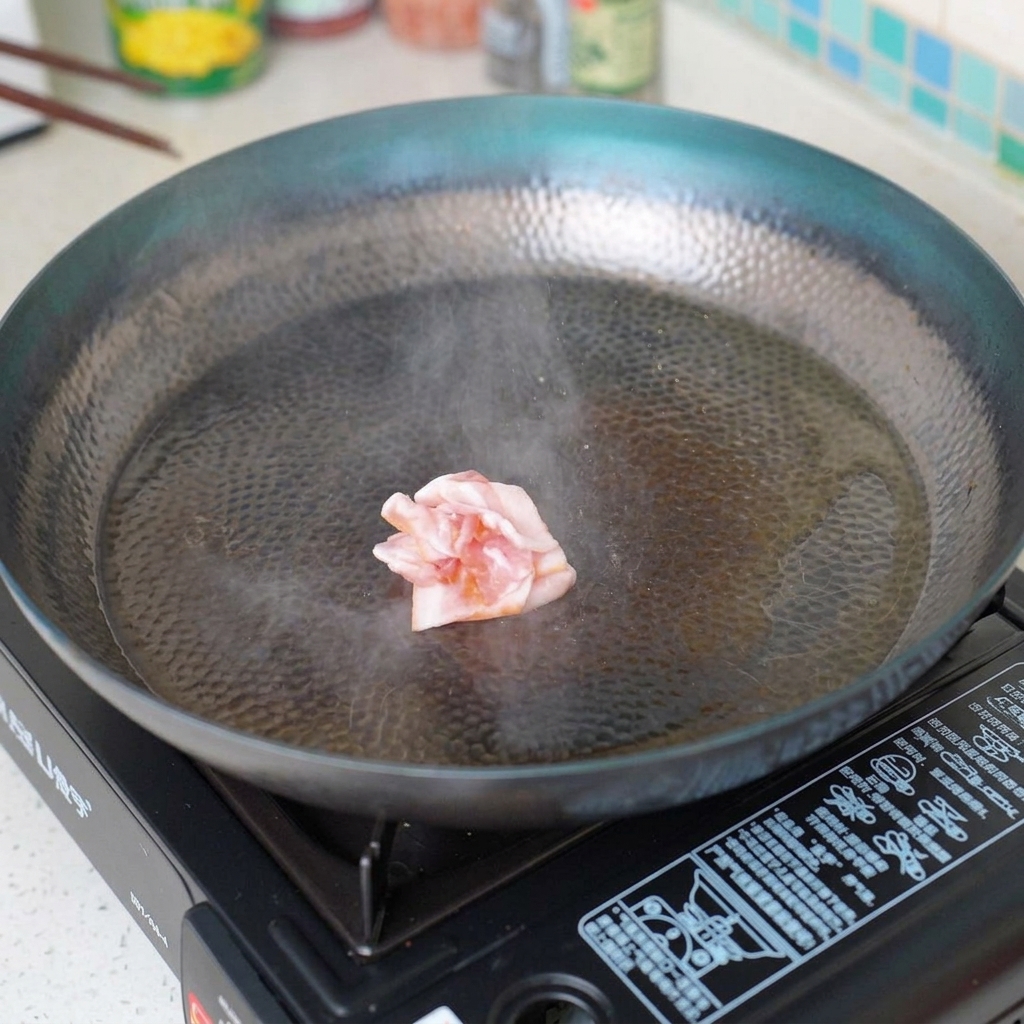 Trozos de tocino friéndose en una sartén caliente hasta quedar crujientes.