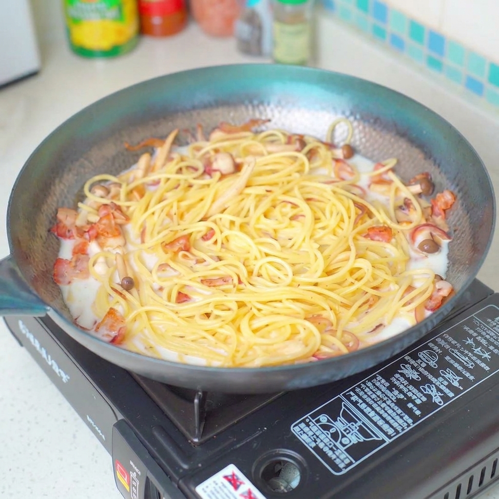 Sazonando el plato de pasta con sal mientras hierve a fuego lento en la sartén.