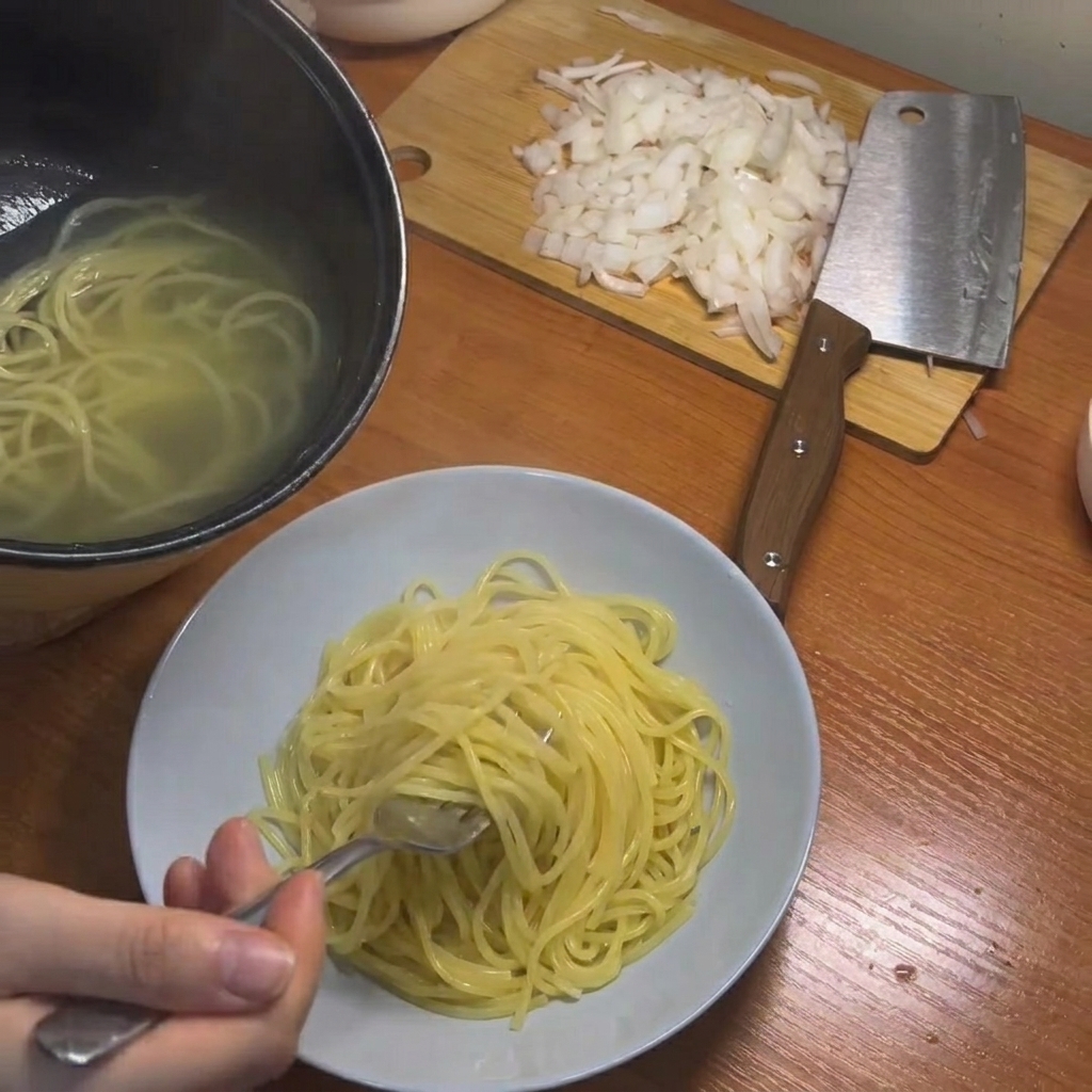 Espaguetis cocinados siendo retirados de la olla usando palillos.