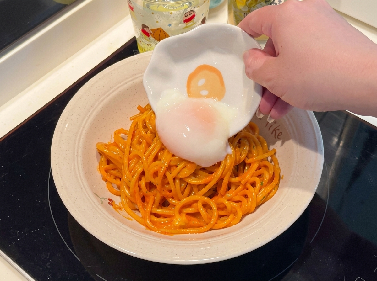Un huevo pasado por agua colocado sobre un plato de espaguetis picantes.