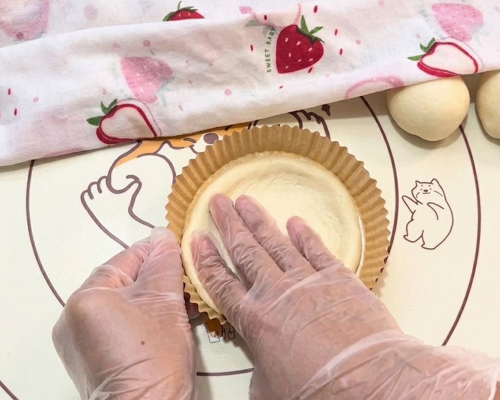 La masa siendo colocada cuidadosamente en la bandeja de papel con guantes.
