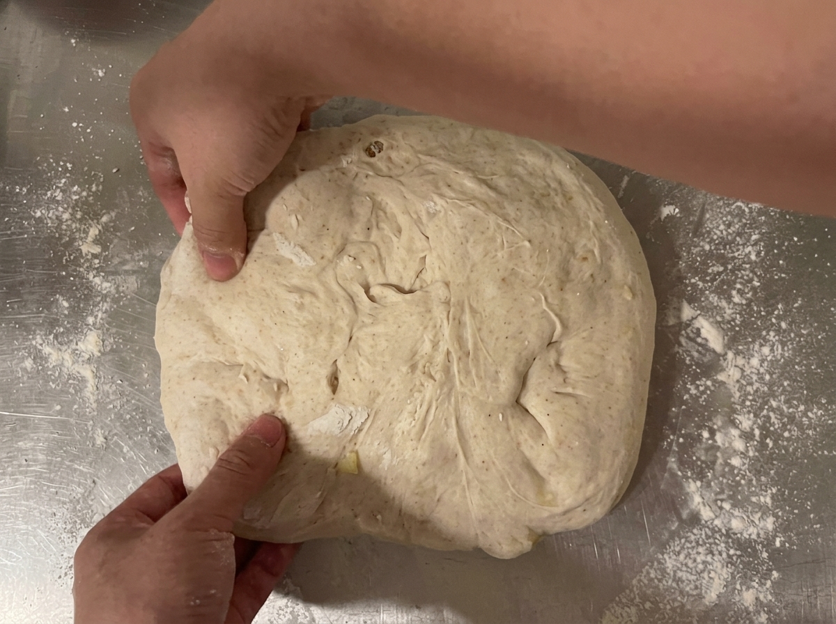 Masa formándose en un cilindro de pan usando el método de triple pliegue sobre la encimera.