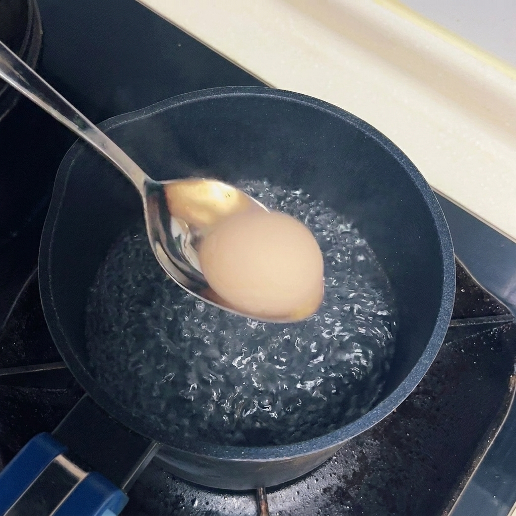 Un huevo siendo sumergido con cuidado en una olla con agua hirviendo a fuego suave.