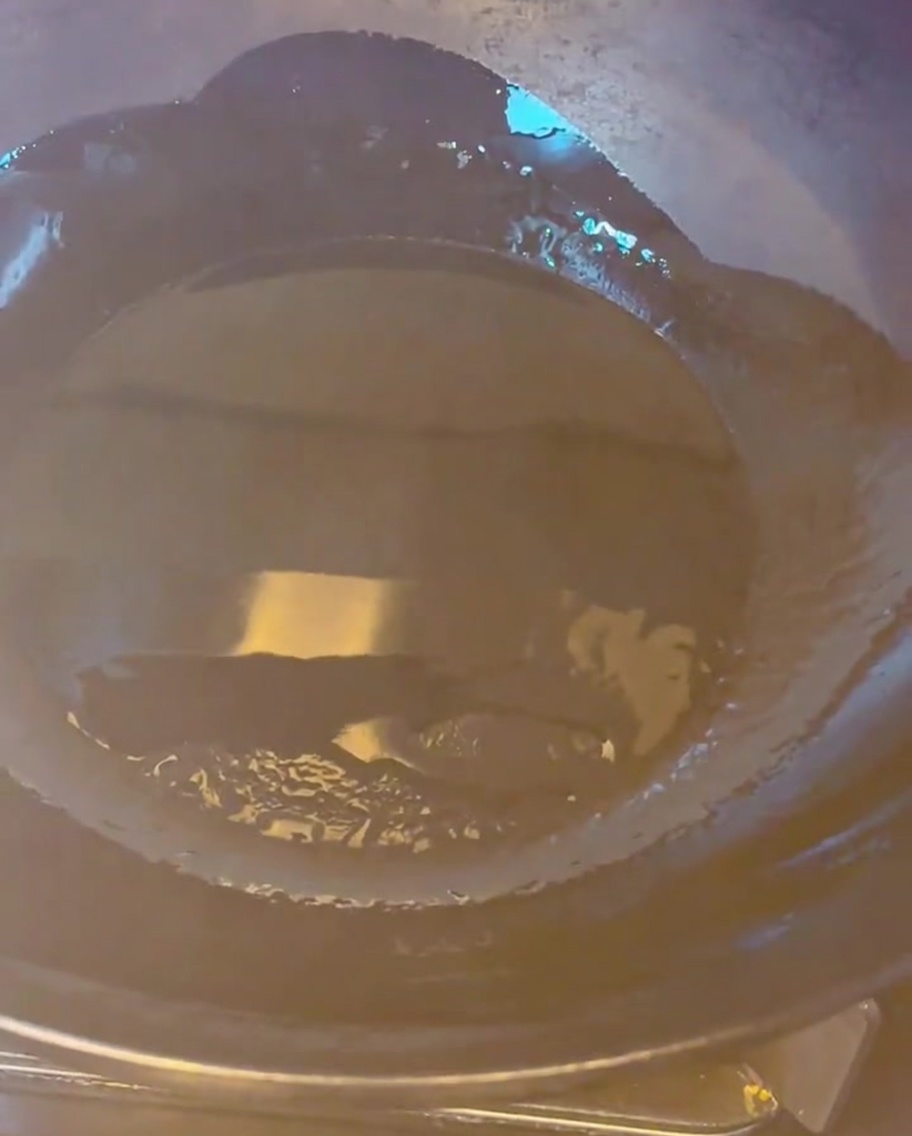 Trozos de panceta de cerdo dorándose en un wok caliente con aceite.