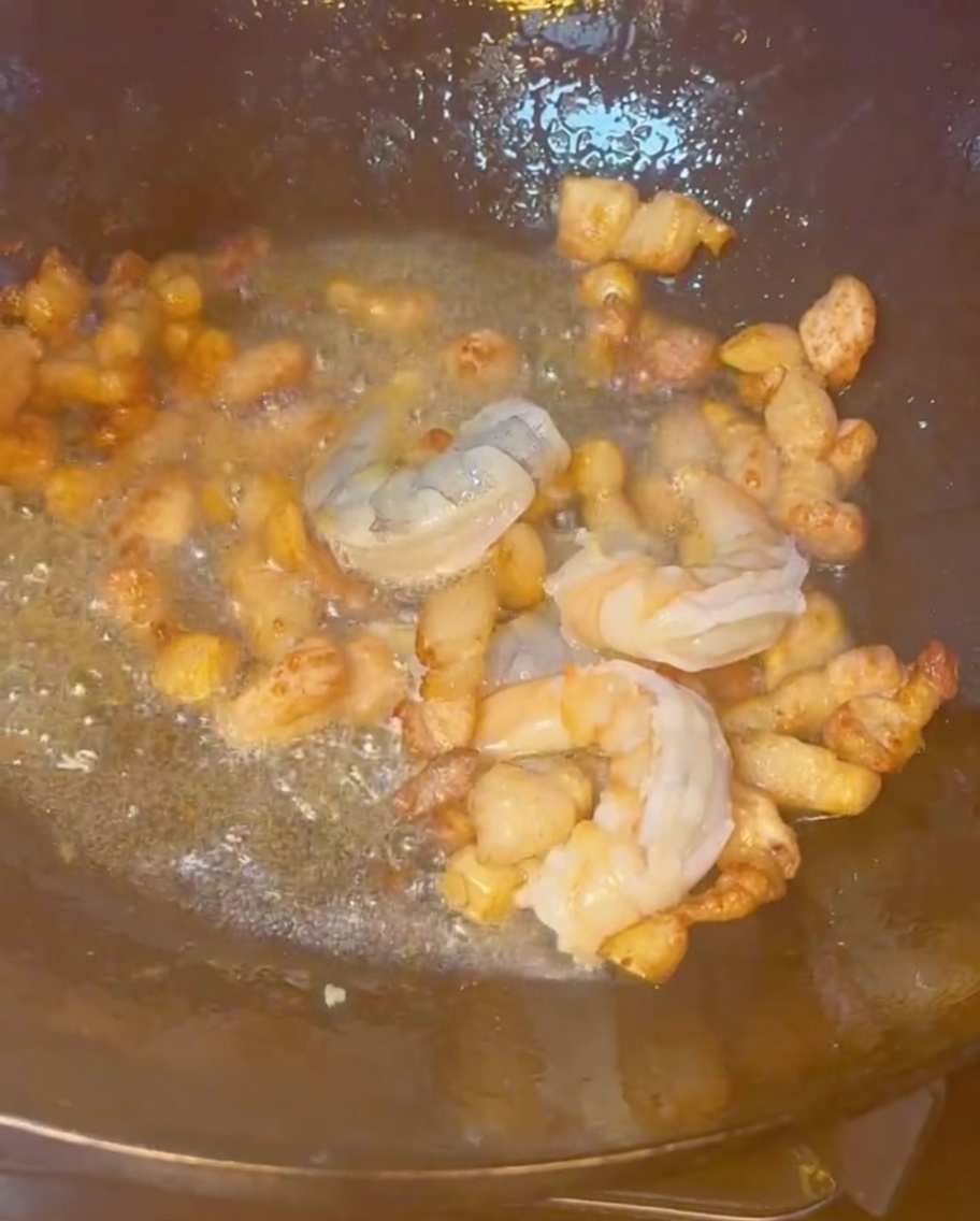 Camarones, panceta de cerdo y otros mariscos mixtos salteándose juntos en un wok caliente.