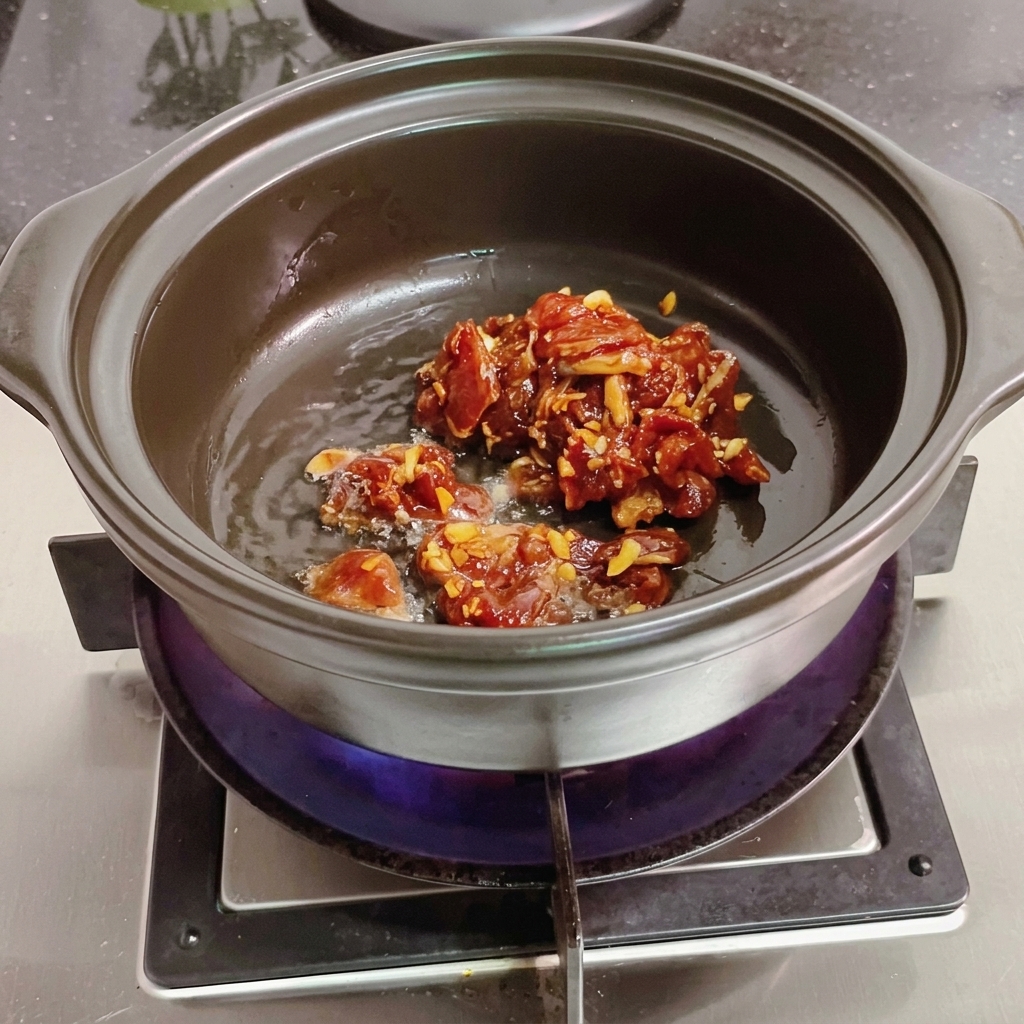 Rodajas de carne removiéndose en una olla de barro con una espátula de madera.