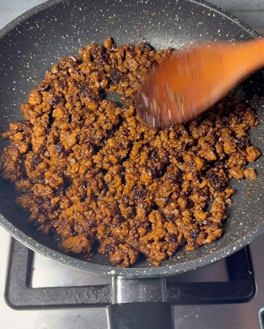 Carne picada siendo salteada en una sartén hasta que esté completamente dorada.