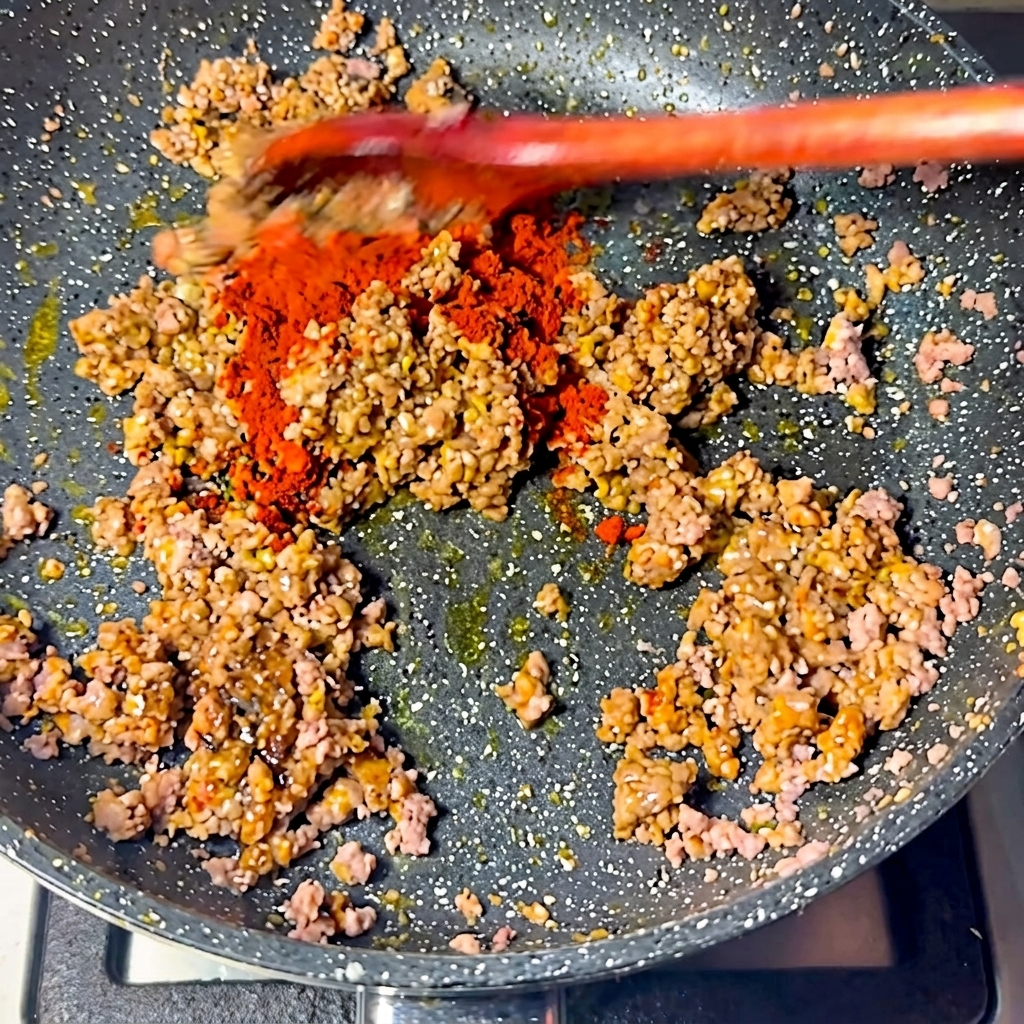 Chile en polvo rojo espolvoreado sobre la mezcla de carne.