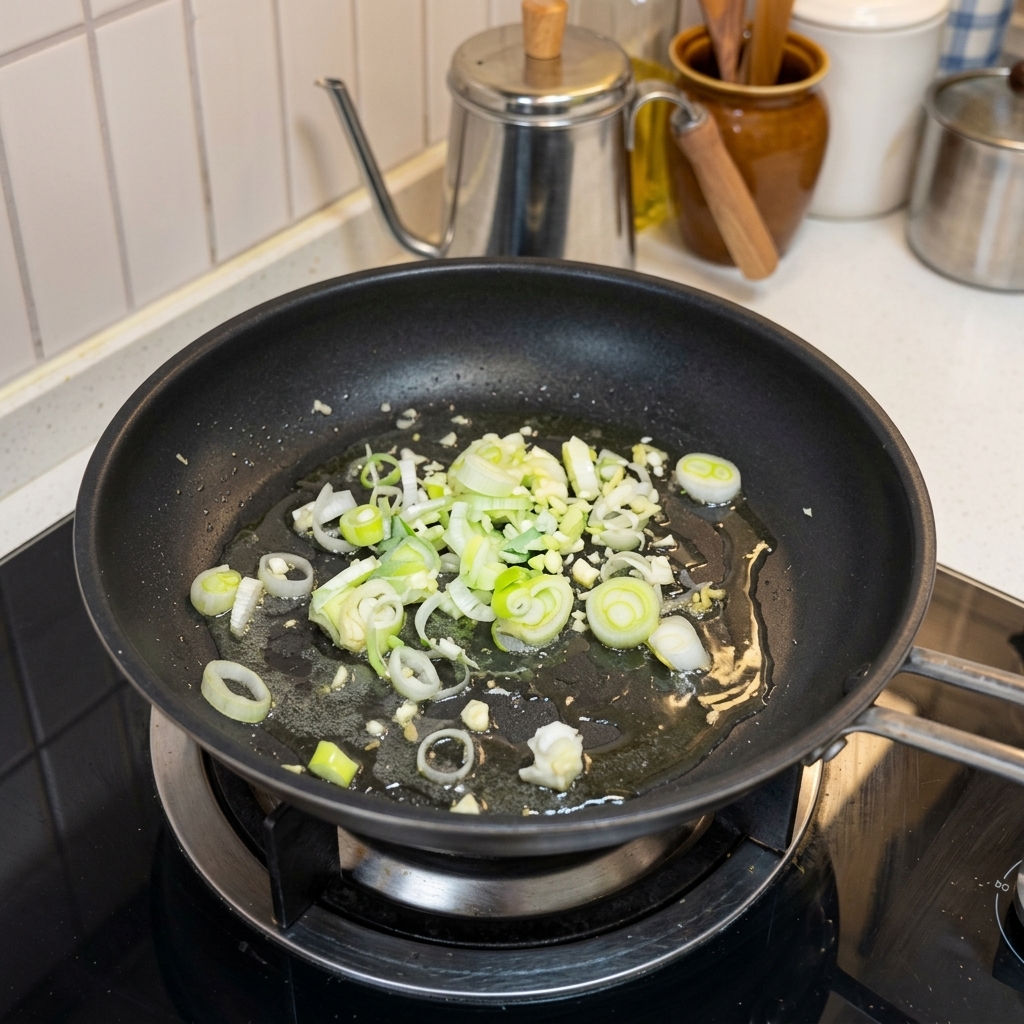 Ajo picado y cebolleta salteándose en una sartén caliente con aceite.