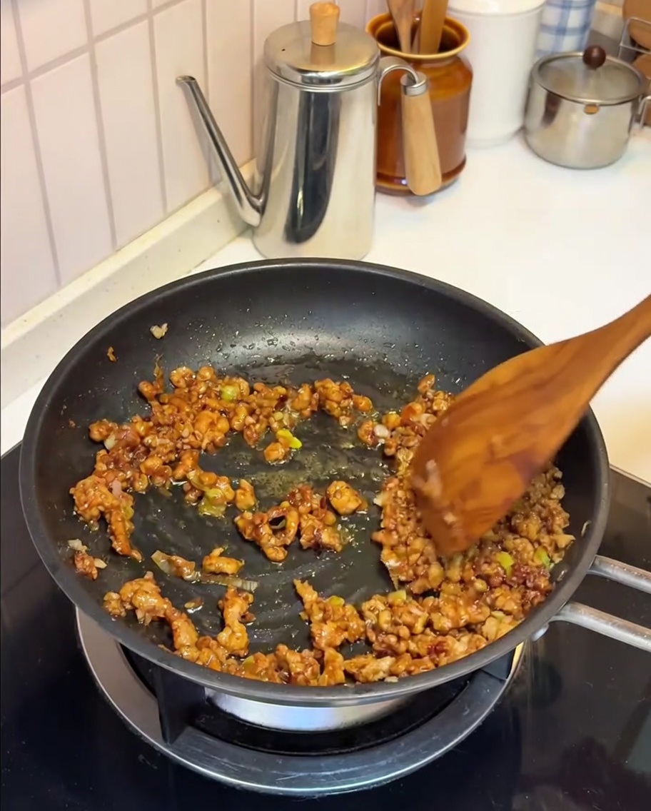 Leche de soja vertiéndose en la sartén con la mezcla de carne y miso.