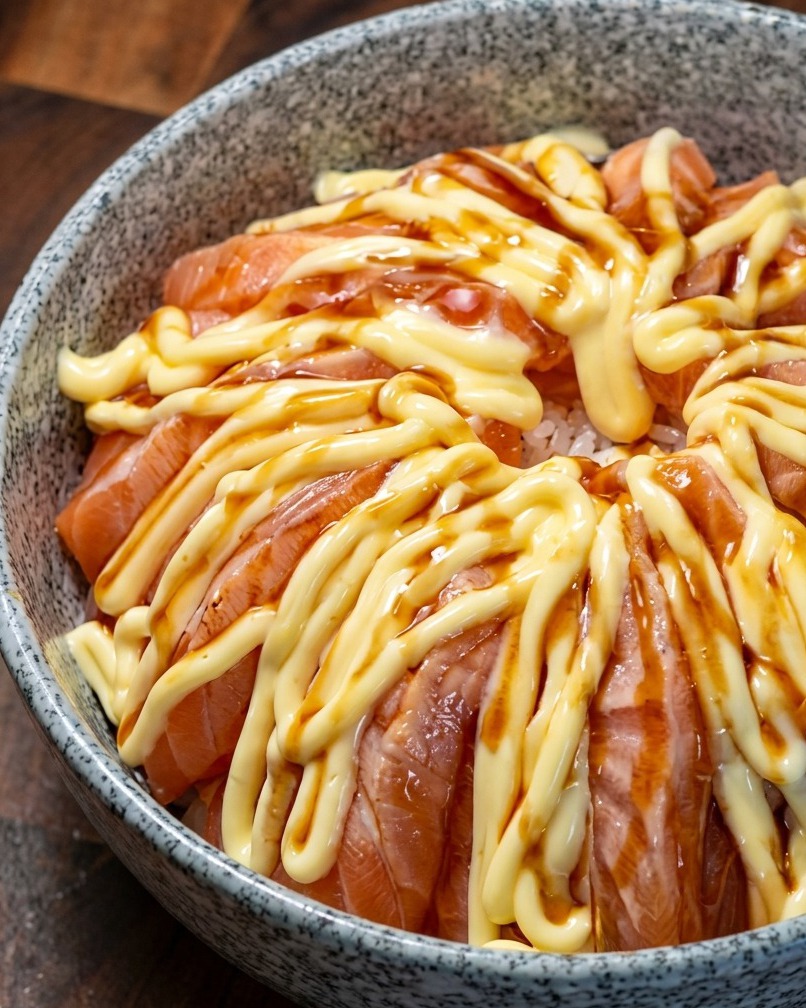 Tazón de salmón rociado con salsa teriyaki sobre la capa de mayonesa.