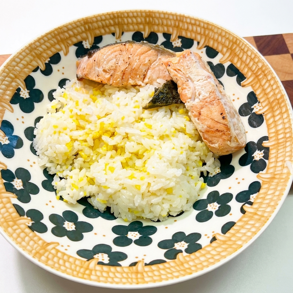 Un bol de cerámica con hermosos motivos lleno de arroz blanco, cubierto con dos trozos de salmón cocinado y algas oscuras.