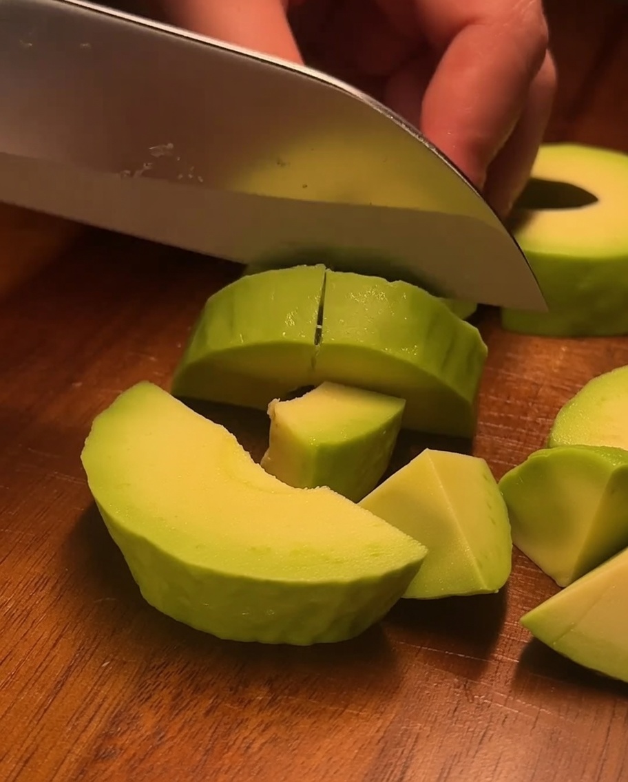 Camarones cocidos cortados en porciones pequeñas del tamaño de un bocado sobre una tabla de madera.