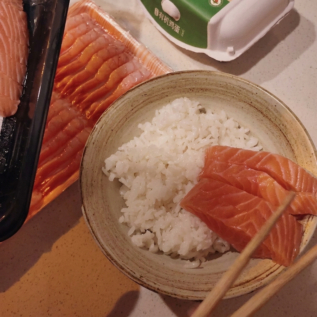 Acomodando láminas de salmón y vieiras sobre el arroz en un tazón.
