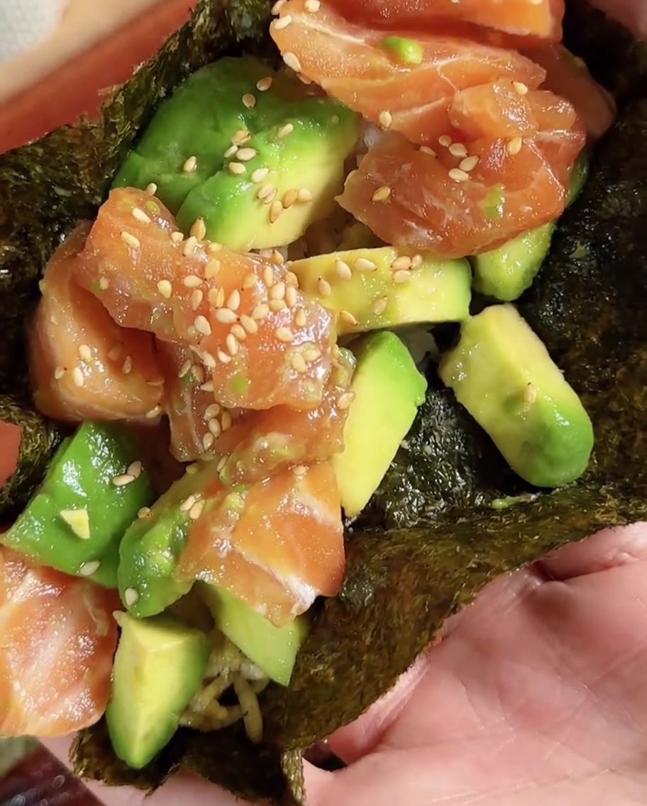Una pieza circular de nori para sushi siendo cortada de una hoja más grande.