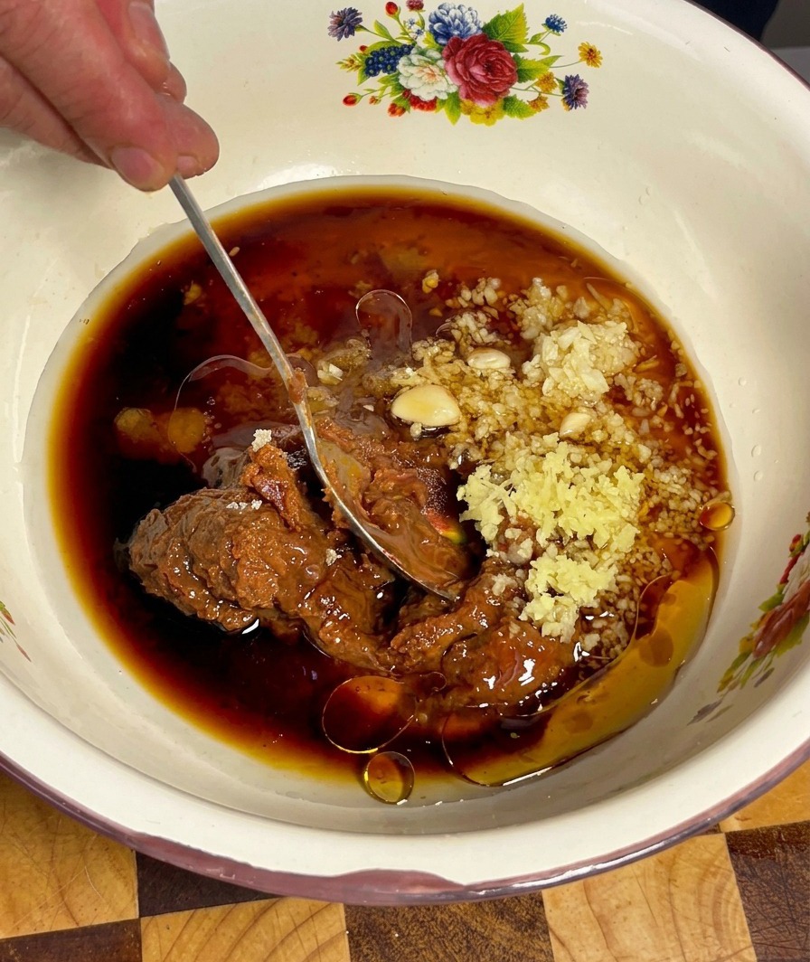 El marinado de Doenjang siendo mezclado con una cuchara hasta obtener una consistencia suave y bien incorporada.