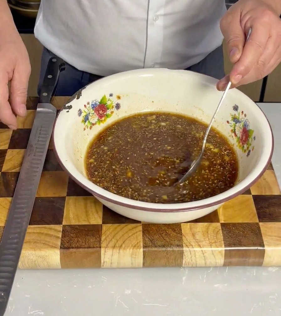 Tiras de panceta de cerdo siendo colocadas en el tazón con el marinado, asegurando que queden bien cubiertas.