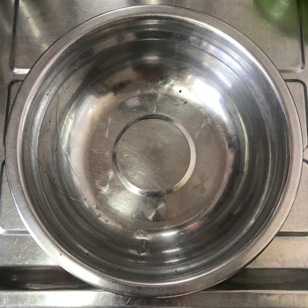 Un primer plano de salsa de chile Tianjin siendo vertida en un bol de mezcla de acero inoxidable.