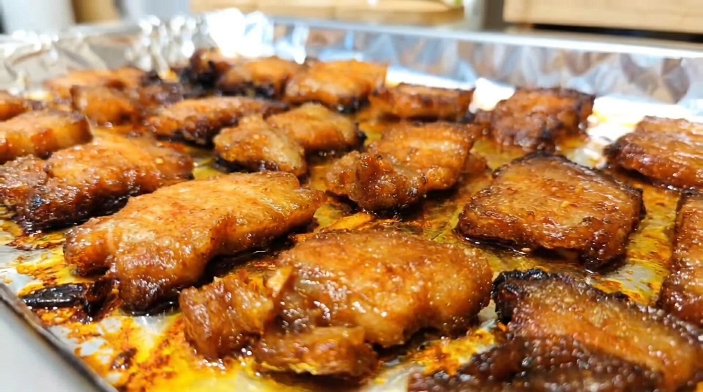 Una bandeja de rebanadas de panceta de cerdo asada, doradas y perfectamente caramelizadas.