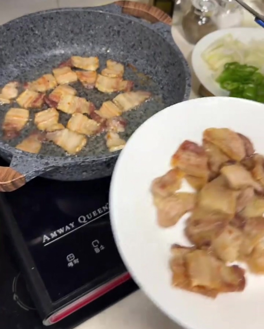 Unas pinzas de metal colocando rebanadas de panceta doradas y crujientes en un plato blanco.