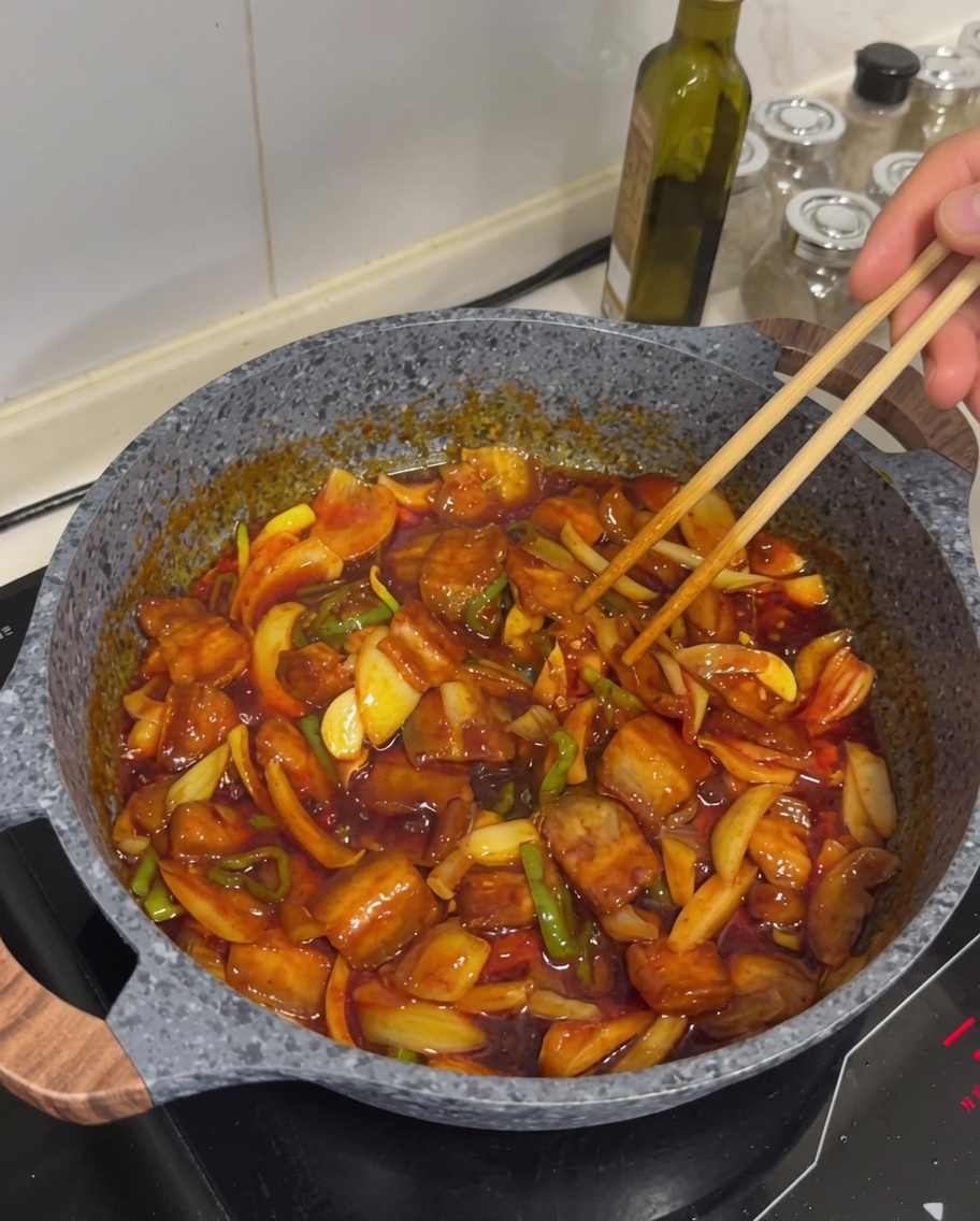 Panceta de cerdo picante terminada en una sartén, espolvoreada con semillas de sésamo.