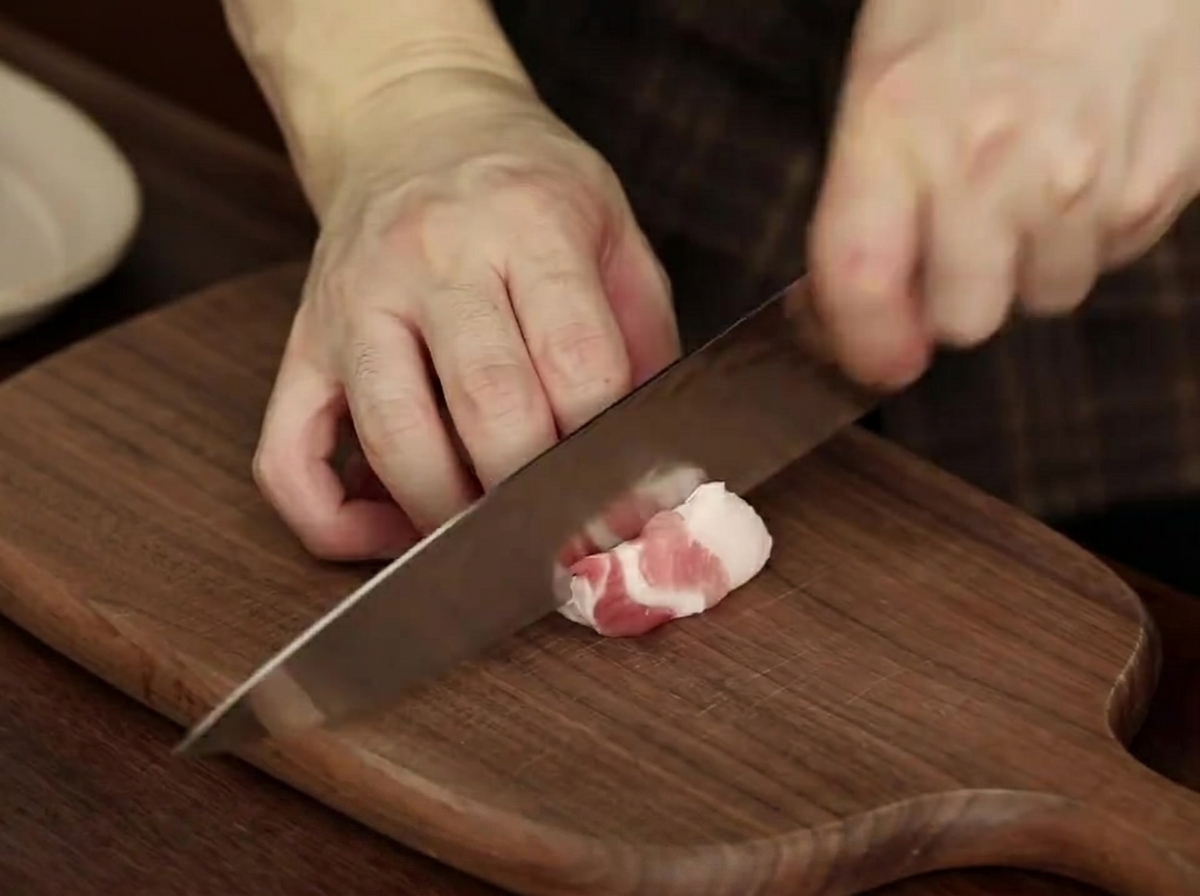Rebanadas de panceta cruda dispuestas ordenadamente en un plato, listas para el estofado.