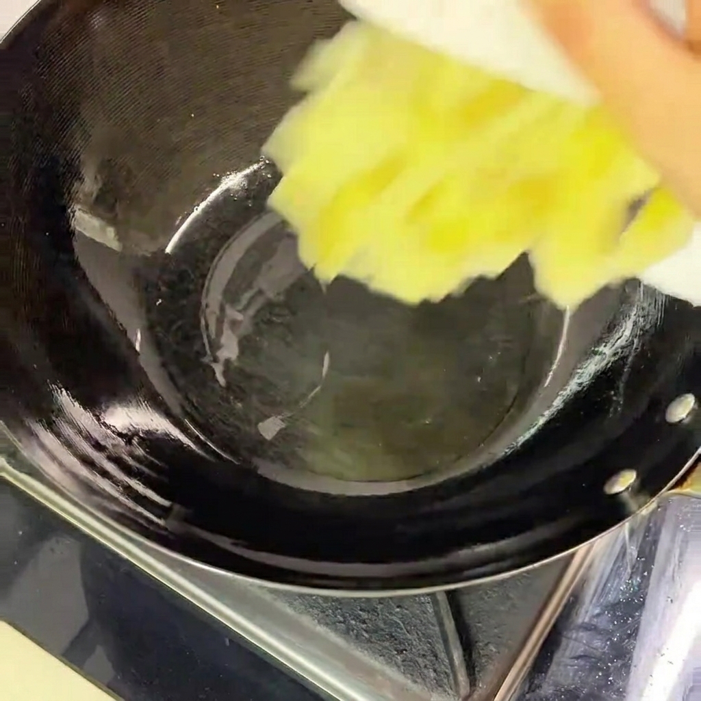 Vertiendo col encurtida picada desde un plato blanco a un wok negro caliente que contiene una fina capa de aceite.