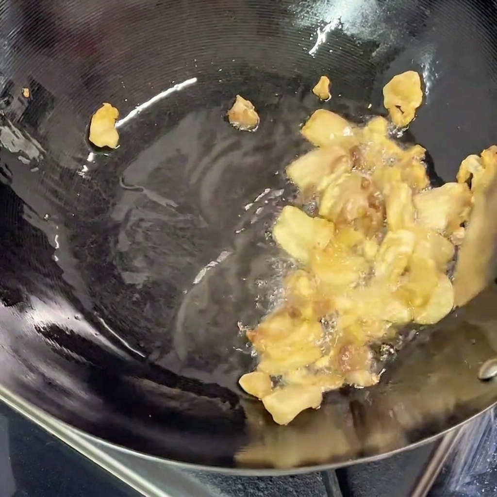 Trozos de panceta friéndose en el wok, con grasa fundida clara visible en el fondo de la sartén.