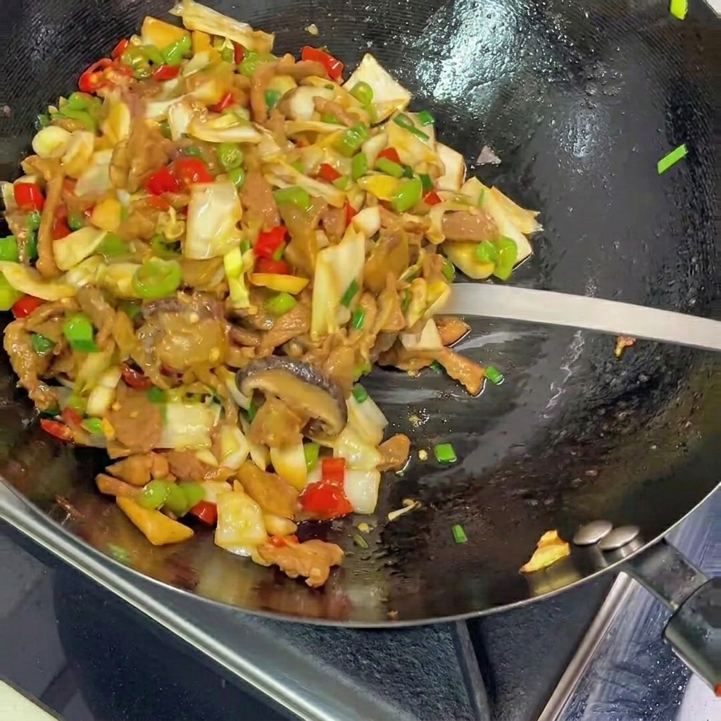 Una espátula de metal sirviendo una colorida mezcla de col encurtida salteada, cerdo y pimientos desde un wok negro a un plato.