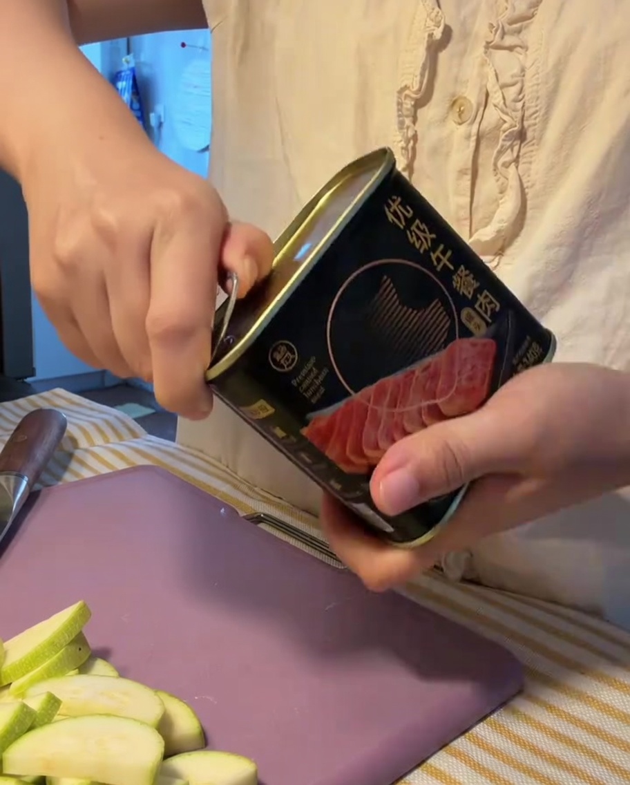 Un bloque de carne de almuerzo siendo retirado de su lata metálica abierta.