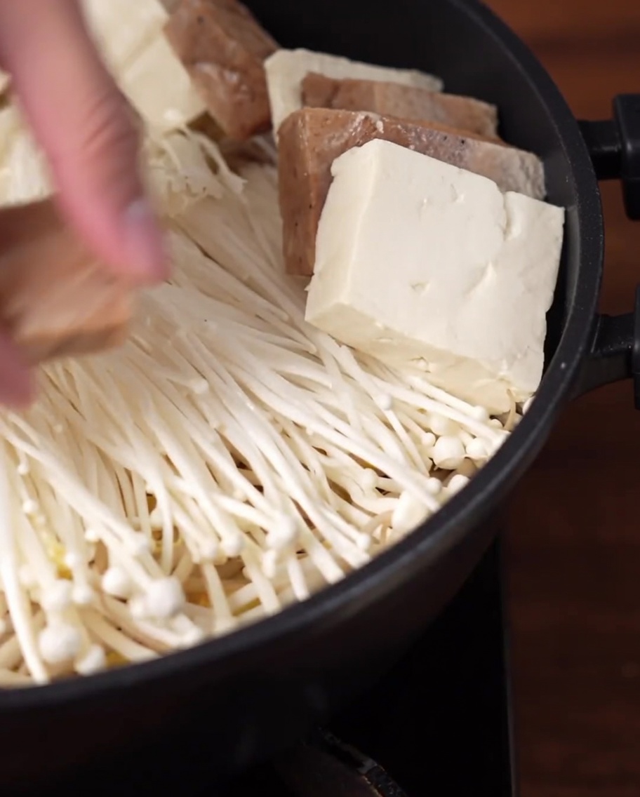 Rodajas de tofu y carne vegana organizadas en un patrón circular dentro de la olla.