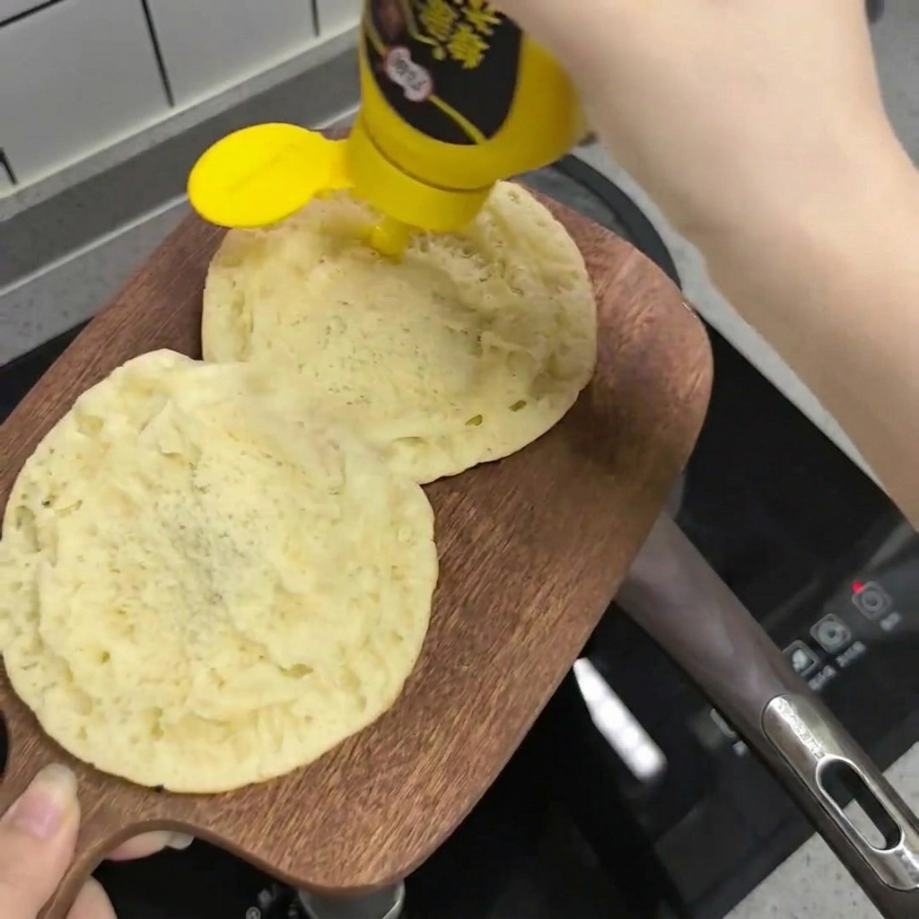 Salsa de miel y mostaza siendo aplicada en zigzag sobre las mitades del pan.
