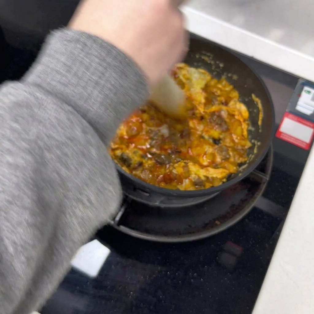 Una espátula dividiendo la tortilla en dos partes en la sartén.