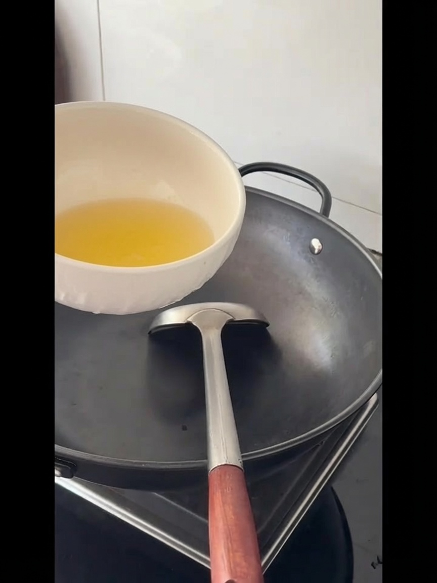 Aceite de cocina siendo vertido en un wok grande y vacío.
