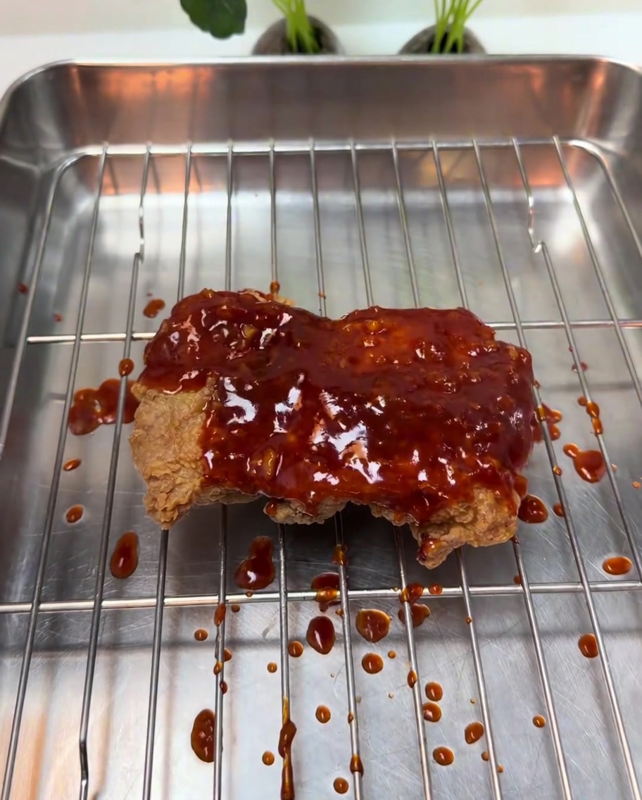 Un glaseado rojo de chile, espeso y burbujeante, cayendo sobre el pollo frito crujiente.