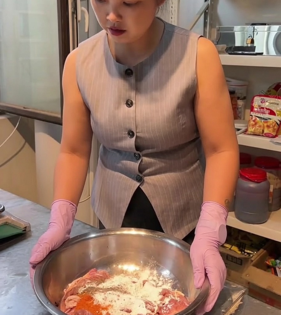 Trozos de pollo crudo mezclados con especias y adobo en un bol grande de acero inoxidable.