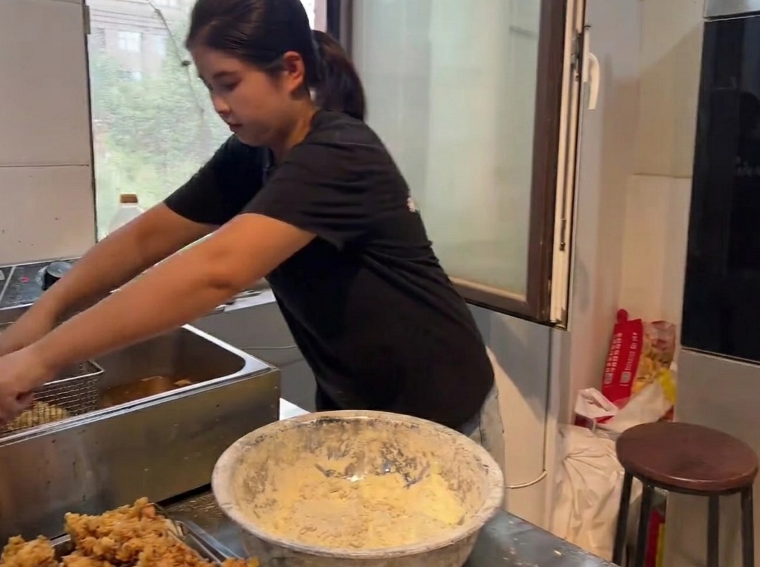 Trozos de pollo frito, dorados y crujientes, siendo sacados de una freidora.