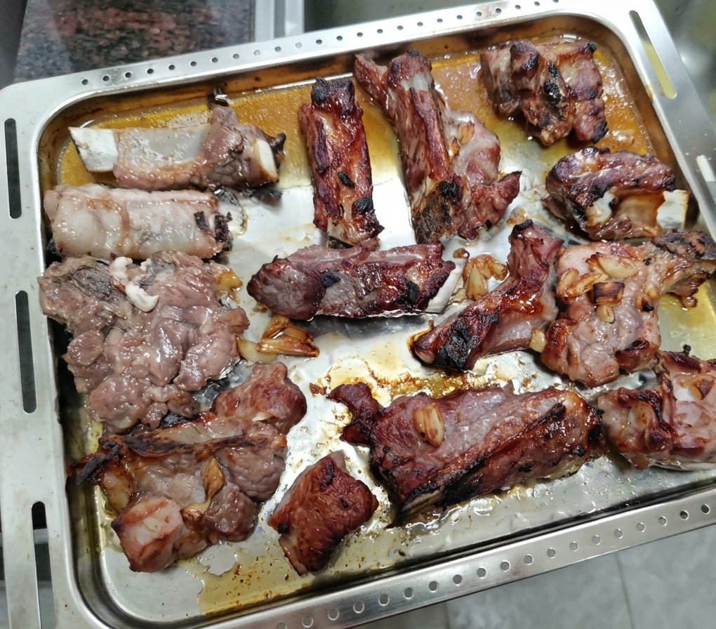 Costillas de cerdo parcialmente asadas en la bandeja, listas para ser pinceladas con miel.