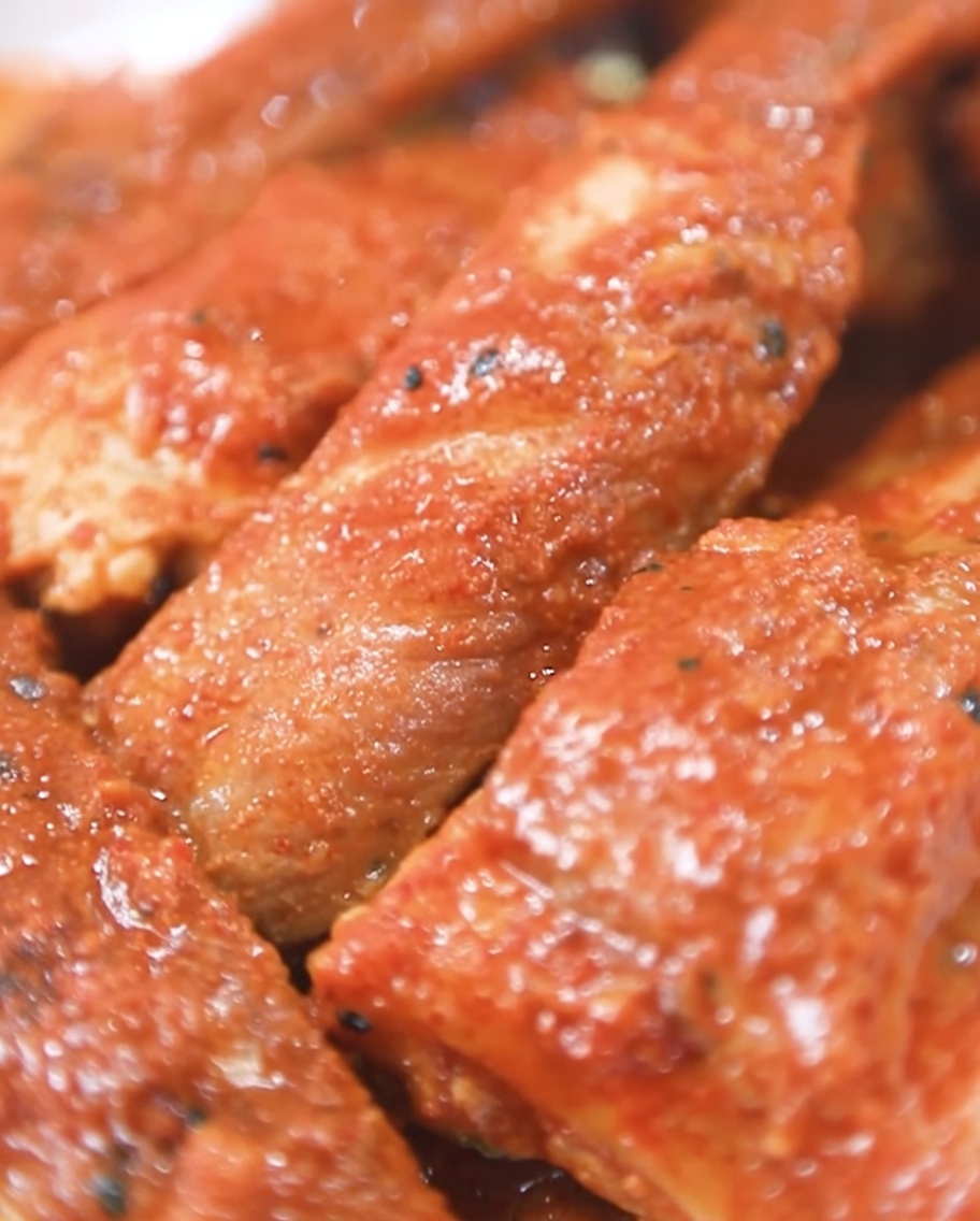 Costillas de cerdo envueltas en papel de aluminio siendo colocadas dentro de un horno para rostizar.