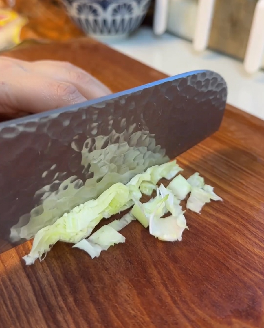 Hojas de lechuga finamente cortadas sobre una tabla de madera.