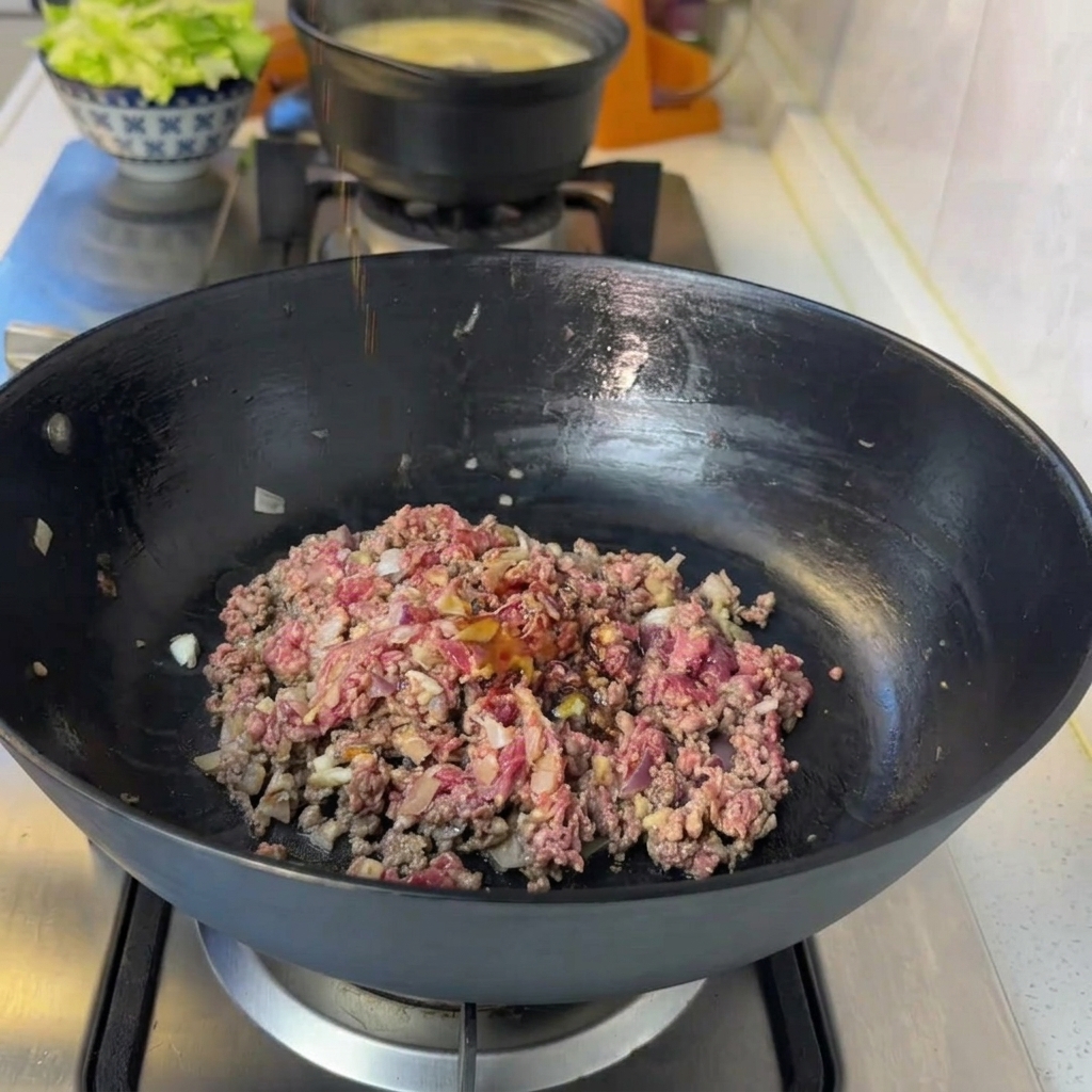 Mezcla de carne en la sartén siendo sazonada con soja, pimienta y kétchup.