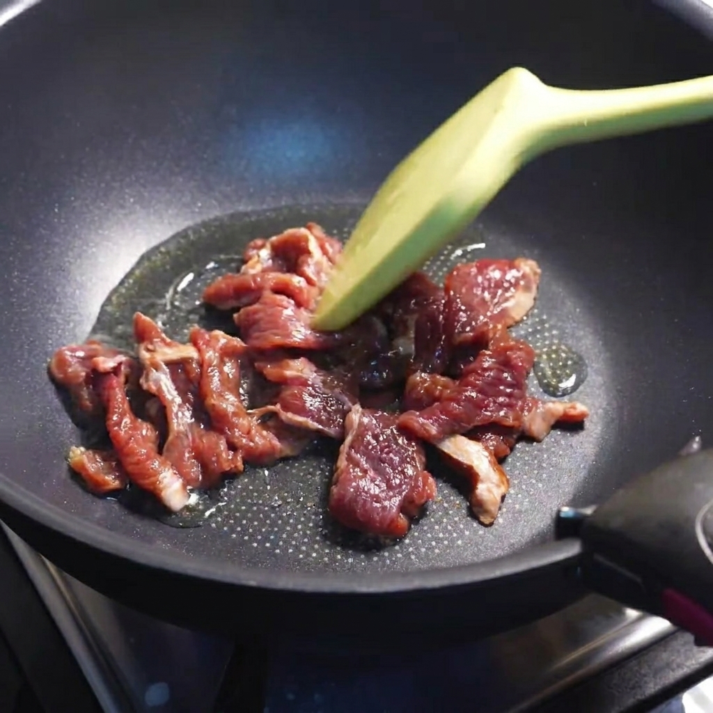 Rodajas de ternera dorándose en una sartén caliente.