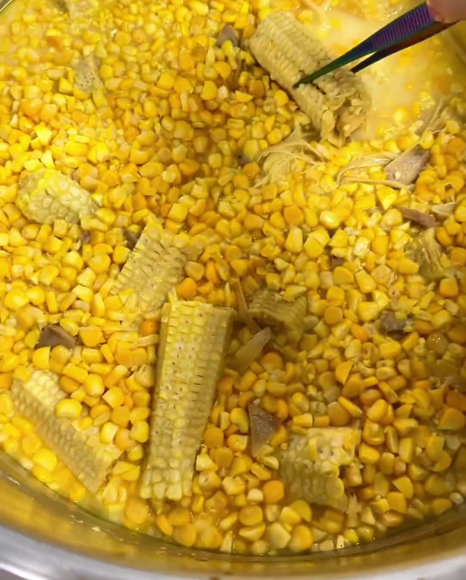 Pinzas retirando la hierba limón y una mazorca de la sopa de elote.