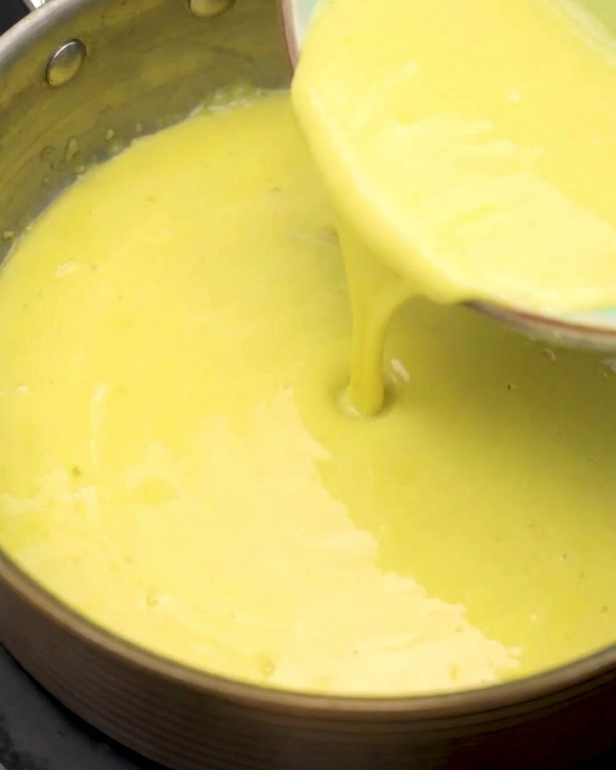 Crema de maíz colada siendo vertida en el cazo con la base de harina y ajo.
