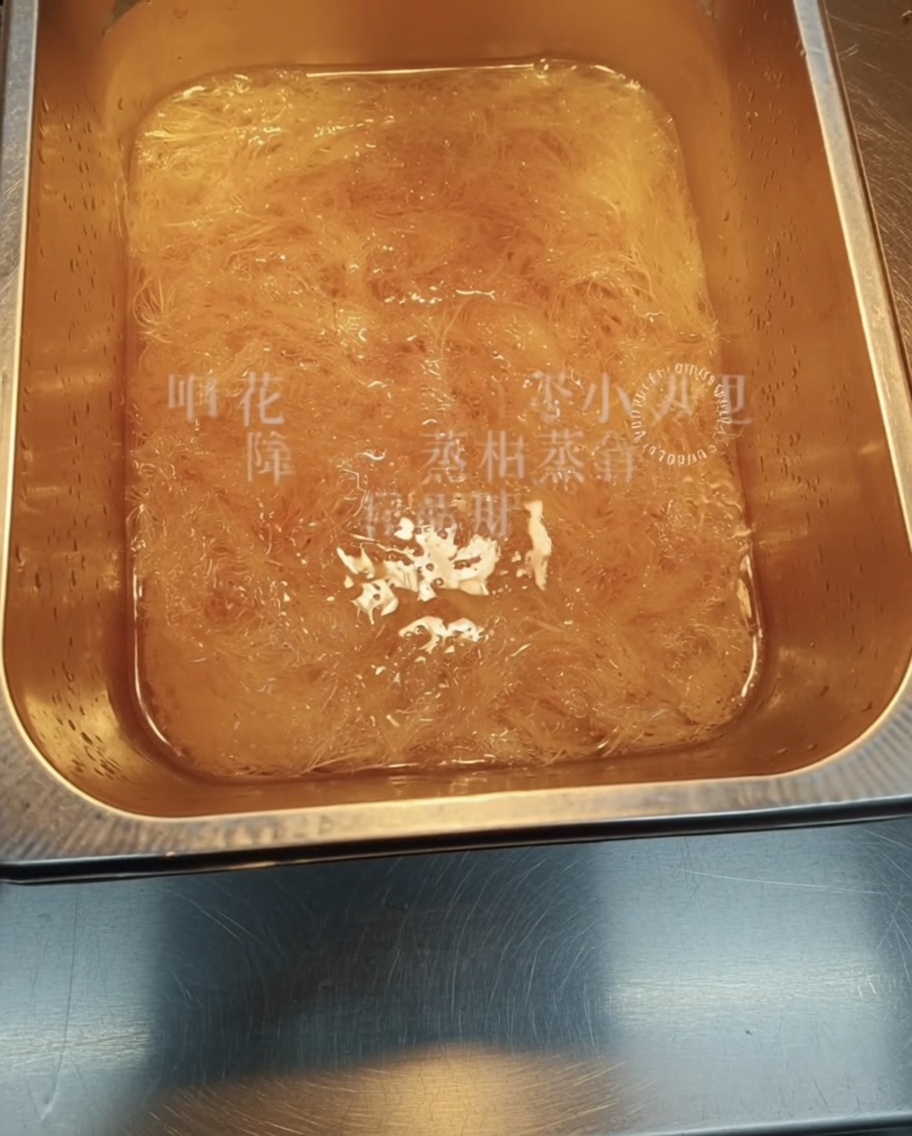 Vista cercana de tiras de agar-agar deshidratado remojándose en un recipiente con agua.