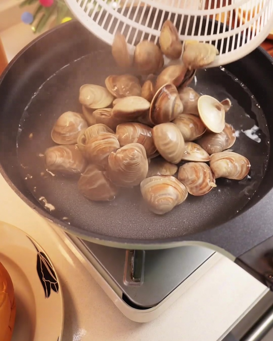 Almejas frescas hirviendo en una olla con agua, abriendo sus conchas.