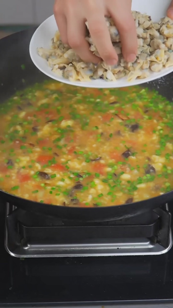 Un tazón de sopa de almejas con geda, con suaves bolitas de harina, almejas jugosas y un rico y sabroso caldo de tomate y patata.